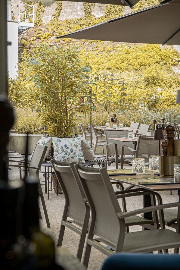 An outdoor dining area with tables and chairs, surrounded by greenery. - Best Western Hotel Spinnerei Linz (Linz)