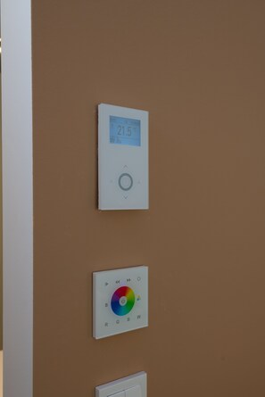 A thermostat and a color control panel mounted on a brown wall. - Best Western Hotel Spinnerei Linz (Linz)