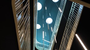 A modern interior with a curved ceiling, hanging lights, and a central circular skylight. - Best Western Hotel Spinnerei Linz (Linz)