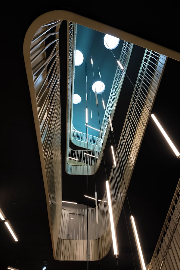A modern interior with a curved ceiling, hanging lights, and a central circular skylight. - Best Western Hotel Spinnerei Linz (Linz)