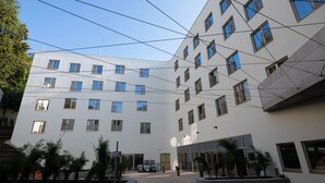 A modern building with multiple floors, large windows, and a courtyard with potted plants. - Best Western Hotel Spinnerei Linz (Linz)