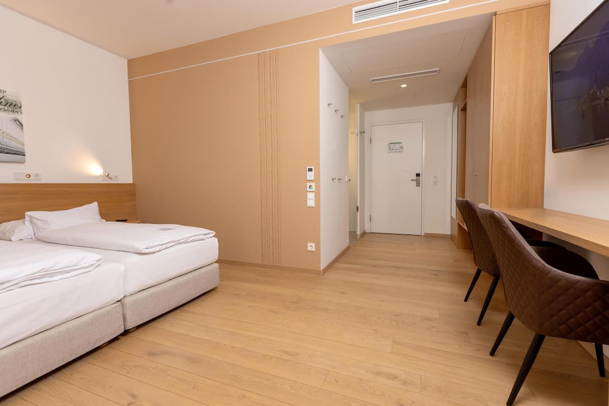A modern hotel room with a bed, a desk, and a TV.