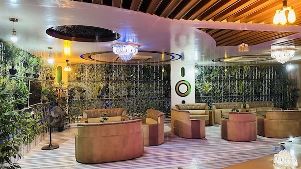 Un salón moderno con diversas opciones de asientos, iluminación decorativa y una pared cubierta de plantas.