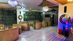 Un salón moderno con asientos cómodos, un televisor grande e iluminación decorativa.