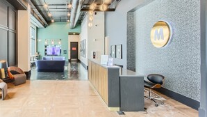 A modern reception area with a reception desk, seating, and a large wall-mounted logo.