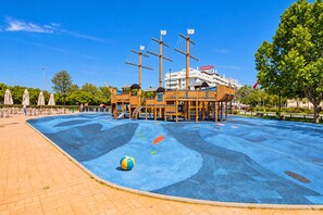 A playground with a ship-themed play structure, a blue play area, and a beach ball.