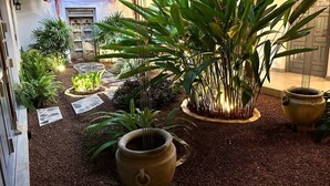 A garden with potted plants, a stone pathway, and a rustic building.