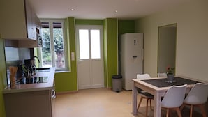 A compact kitchen with a dining area, a refrigerator, and a window with a view of greenery.