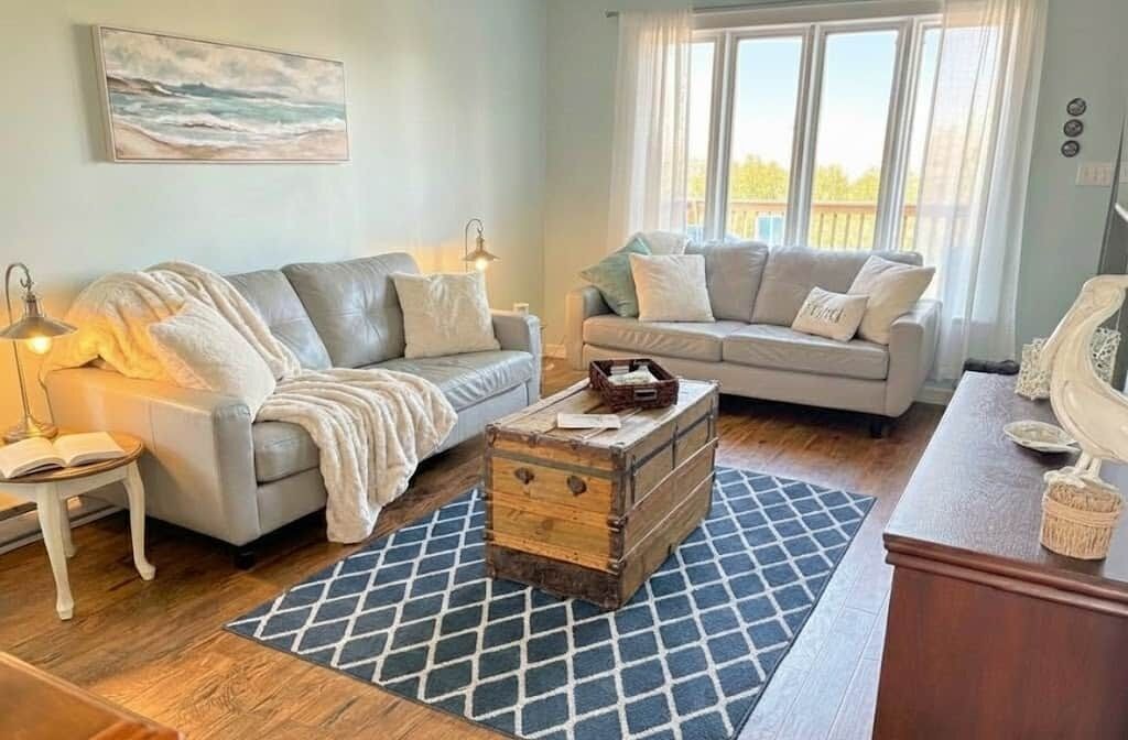 Un salon avec deux canapés, une commode en bois et un tapis à motifs.