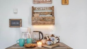 Ein rustikaler Holz-Kaffeeplatz mit einem Schild, das „Diese Küche ist mit Liebe gewürzt“ sagt, einem Kaffeeschild und einem Holzklopper.