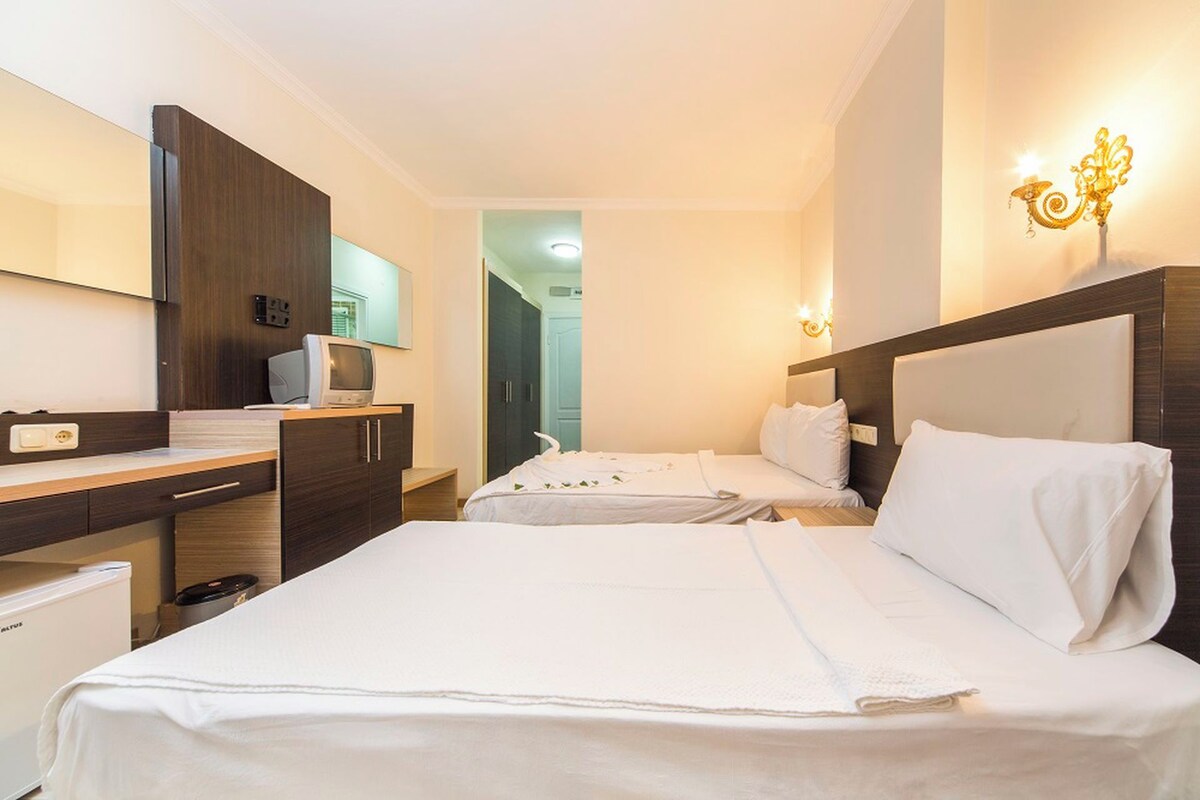A hotel room with two beds, a desk, a television, and a minibar.