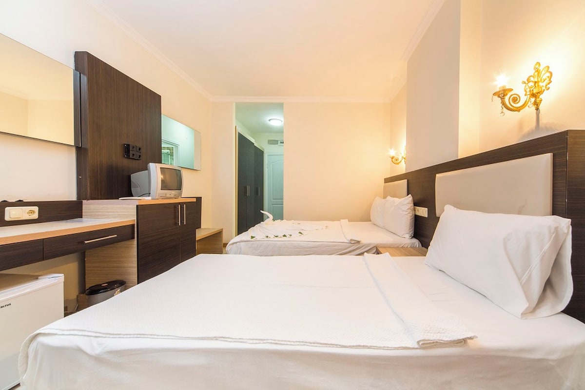 Una habitación de hotel con dos camas, un escritorio, un televisor y un mini bar.