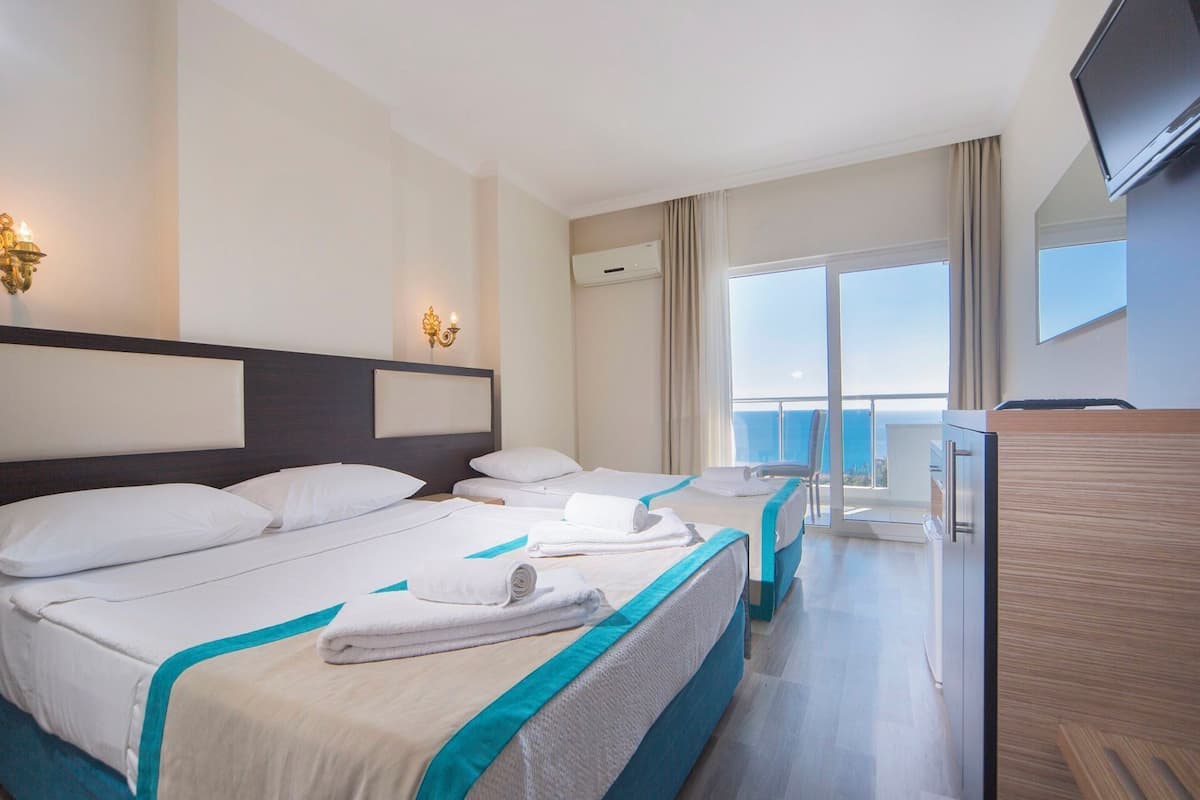 A hotel room with two beds, a TV, a balcony with a view, and a minibar.