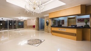 Zona de recepción con candelabro, mostrador y un diseño decorativo en el suelo.
