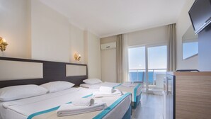 Habitación de hotel con dos camas, televisión, balcón con vistas y minibar.