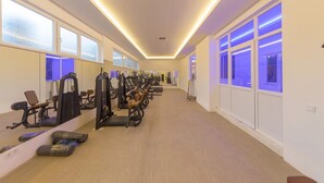 Un gimnasio con máquinas de cardio, pesas y colchonetas de ejercicio.