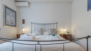 A neatly made bed with white linens, two bedside tables with lamps, and a framed picture on the wall. - Italian Experience- Casale Al Mare (Montorso)