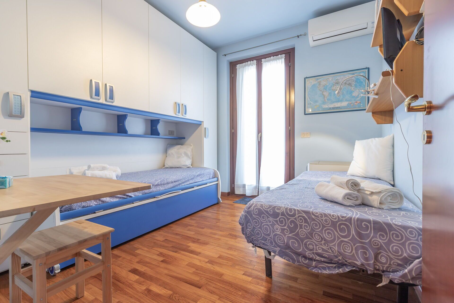 A compact bedroom with a bed, a desk, and a blue sofa bed.