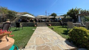 Eine Außenpatio-Terrasse mit Steinboden, Sitzgelegenheiten und Sonnenschirmen.