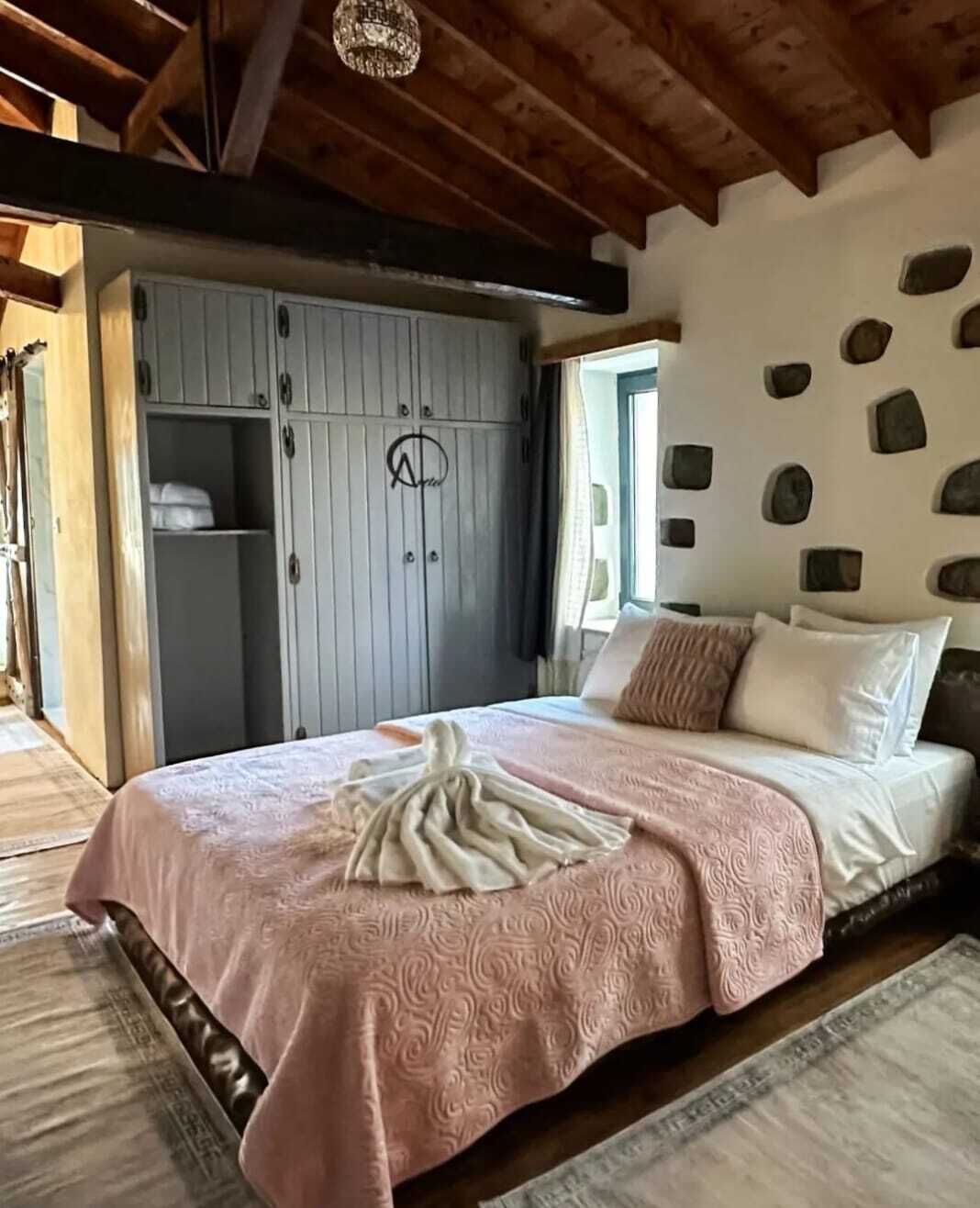 A bedroom with a bed, a wardrobe, and a stone wall.