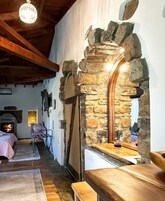 Un interior rústico con un arco de piedra, vigas de madera, una chimenea y una zona de estar acogedora.