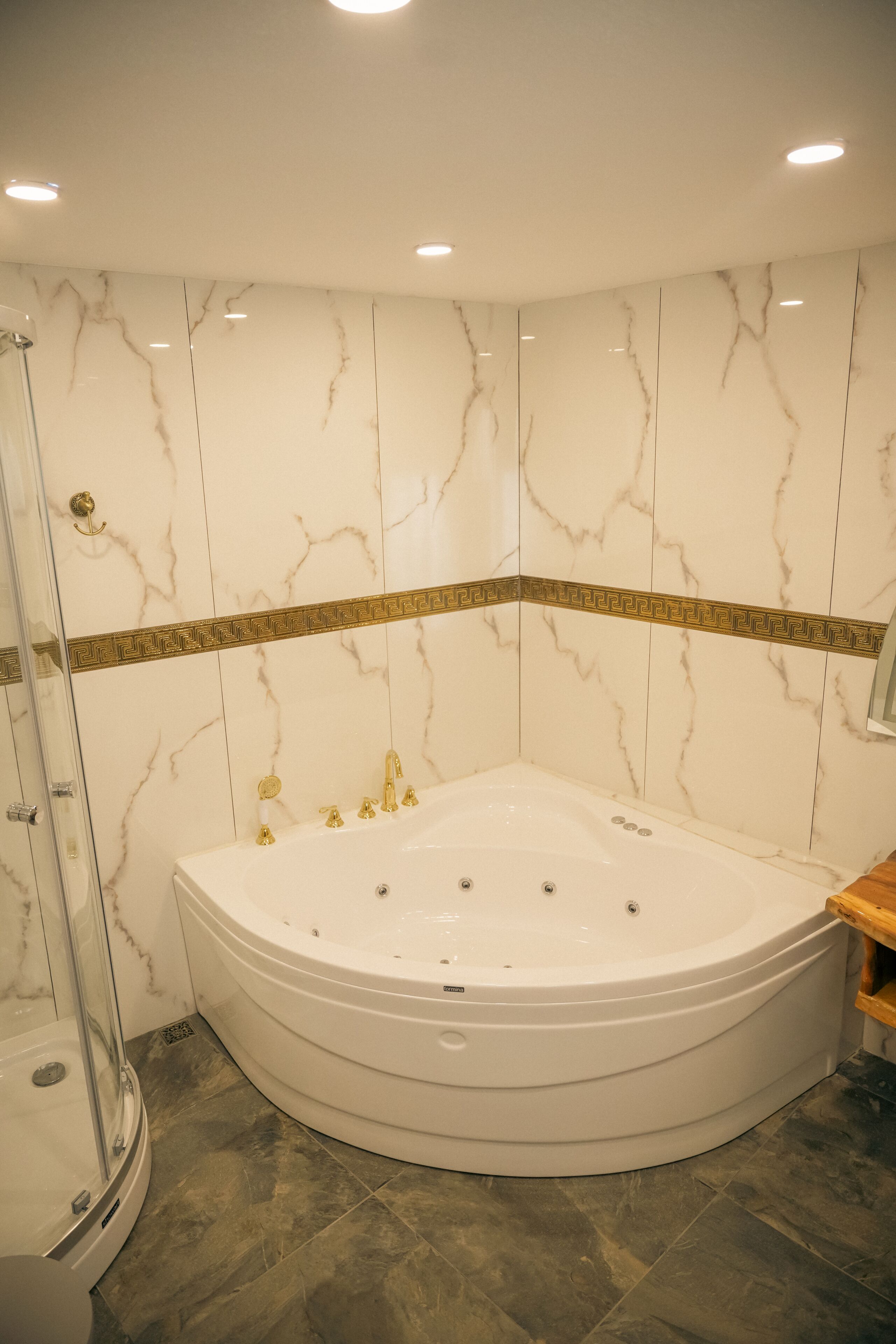 Un baño con una bañera grande, cabina de ducha de vidrio y paredes de mármol.