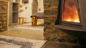 Ein Steingewölbe führt in einen Raum mit Kamin, Fernseher und einem Holztisch.