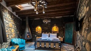 Ein gemütliches Schlafzimmer mit einer Steinwand, einem Kamin, einem Bett und einem blauen Sessel.