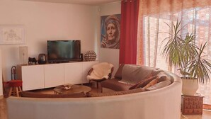 A living room with a sofa, a television, a fireplace, and a large potted plant. - House and outbuilding at the foot of the Alps (Eyguières)