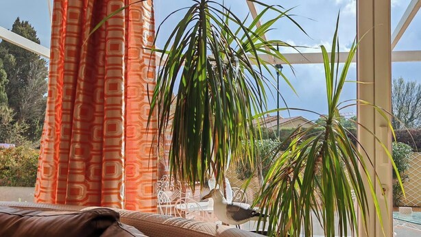 A sunlit room with a view of a swimming pool, a hammock, and a potted plant. - House and outbuilding at the foot of the Alps (Eyguières)