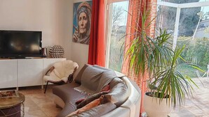 A living room with a sofa, a television, a coffee table, and a potted plant. - House and outbuilding at the foot of the Alps (Eyguières)