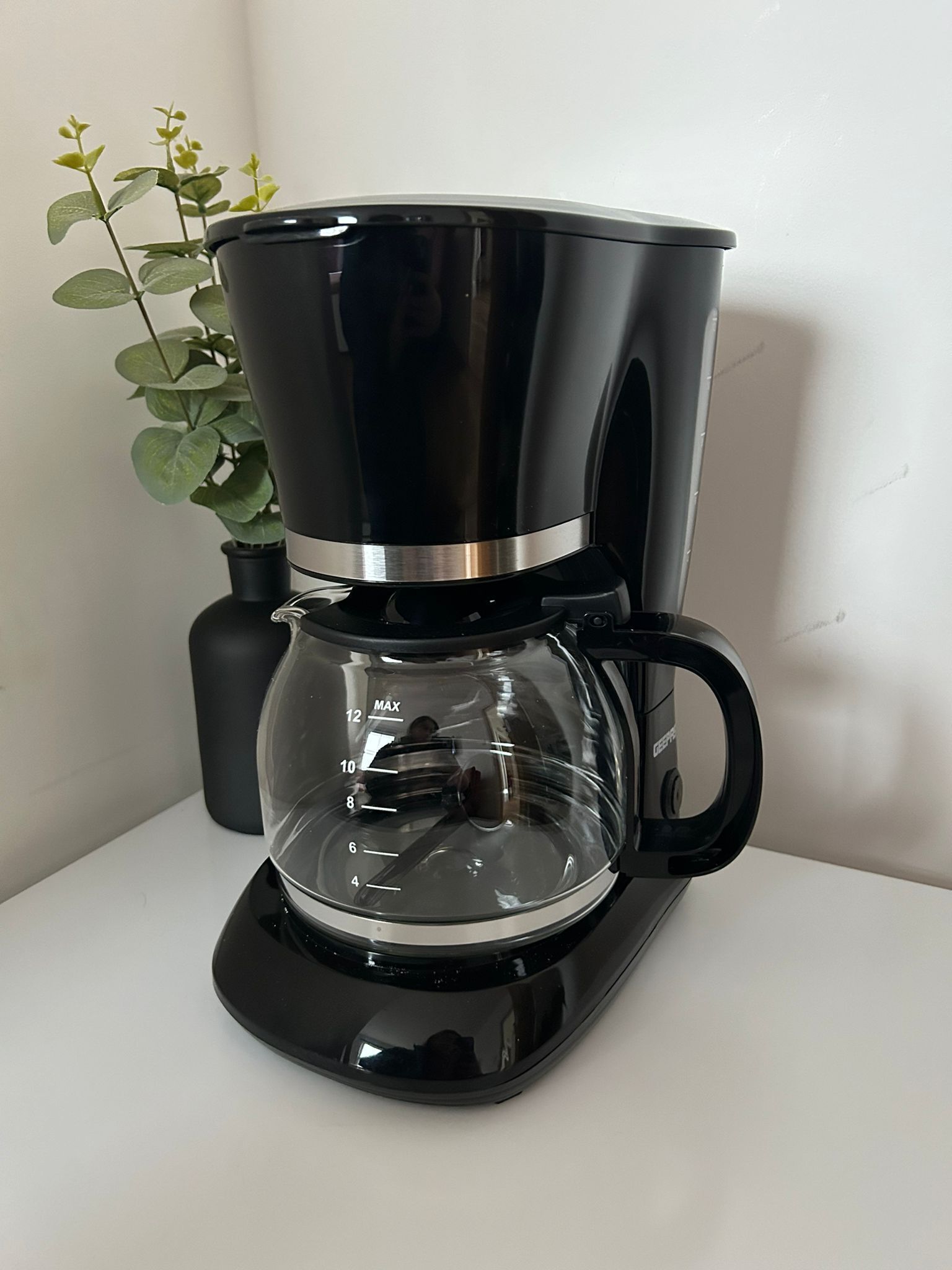 A black coffee maker with a clear carafe and a scale marked from 4 to 12.