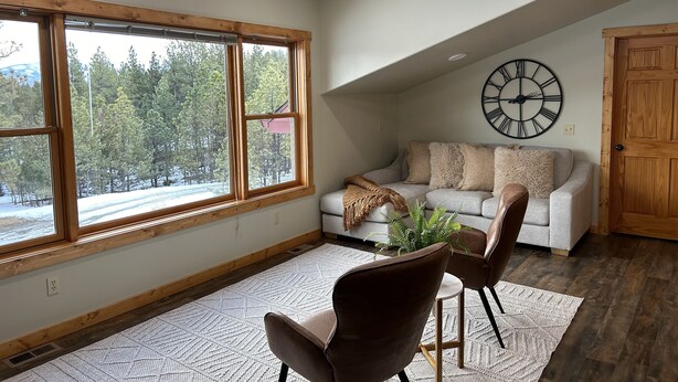 Ein gemütliches Wohnzimmer mit großem Fenster, Deckenventilator, einer Uhr und einer Holztür.