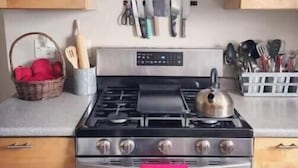 Una cocina con armarios de madera, estufa de acero inoxidable y campana extractora.