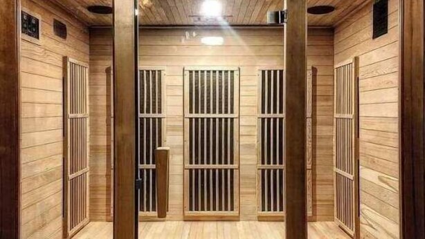 Una sauna con paredes y bancos de madera, un sistema de ventilación central y una luz en el techo.