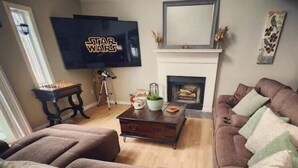 Una sala de estar con un televisor de pantalla plana grande, una chimenea y un sofá.