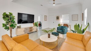 Ett modernt vardagsrum med en platt-TV, två soffor, ett soffbord och en takfläkt.