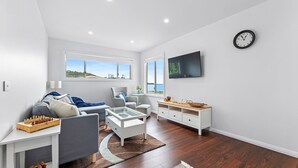En moderne stue med sofa, lænestol, sofabord og fjernsyn.