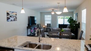 A modern kitchen with granite countertops, a stainless steel sink, and pendant lighting. - Near Airport & Beach Fully Fenced House (Jacksonville)