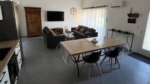 A spacious living area with a dining table, sofas, and a kitchen area. - Gîte du Pommier 🍎 (Legé)