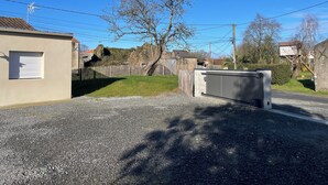 A residential area with a house, a fenced yard, and a gravel driveway. - Gîte du Pommier 🍎 (Legé)