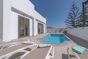 A pool area with lounge chairs and a view of mountains. - CASA MAELLE (Playa Blanca)