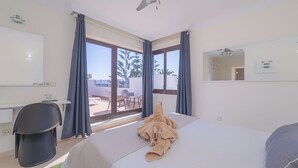 Une chambre d’hôtel avec un lit, un bureau, une chaise et une grande fenêtre avec des rideaux.