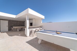 A modern outdoor pool area with a pool table, seating, and a bar area. - CASA MAELLE (Playa Blanca)