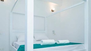 A white four-poster bed with a teal bedspread and two rolled towels. - Angani Apartment : 3 Bedroom all-ensuite apartment in Mombasa (Mombasa)