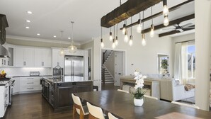 Une cuisine spacieuse dotée d’un grand îlot central, de meubles blancs et de luminaires modernes.