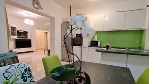 A modern kitchen with white cabinets, a green countertop, and a dining area with a black table and chairs. - Luxury apartment Ani - Three Bedroom Apartment with terrace and Swimming pool (Sutivan)