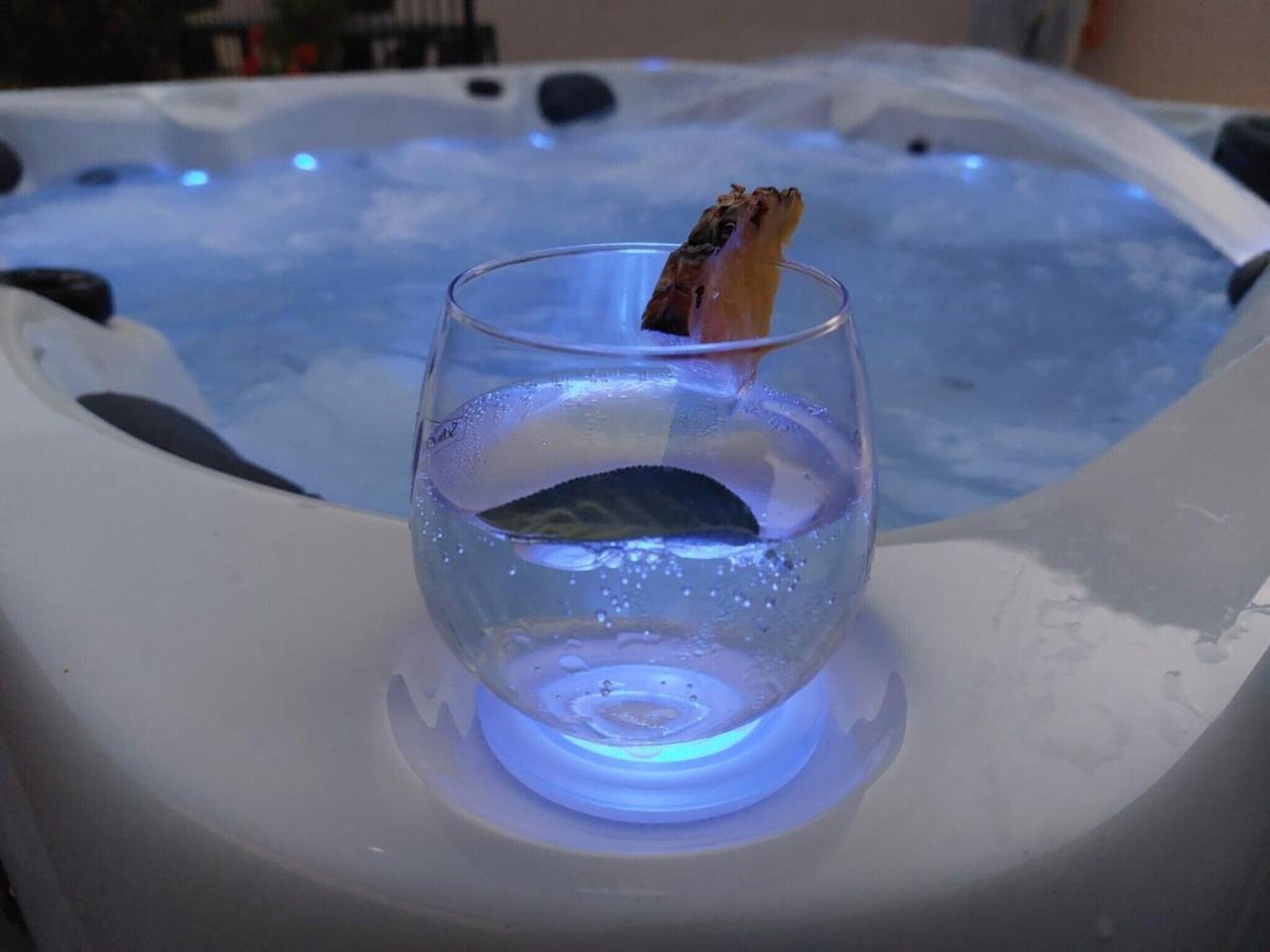 Un vaso de agua sobre una superficie caliente, con un jacuzzi al fondo.