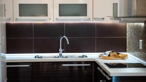 A modern kitchen with dark cabinetry, a stainless steel sink, and a microwave above the counter. - Apartment Adrian 2BR apartment with balcony (Dubrovnik)