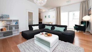 A modern living room with a black sectional sofa, a white coffee table, and a unique spherical ceiling light. - Apartment Adrian 2BR apartment with balcony (Dubrovnik)